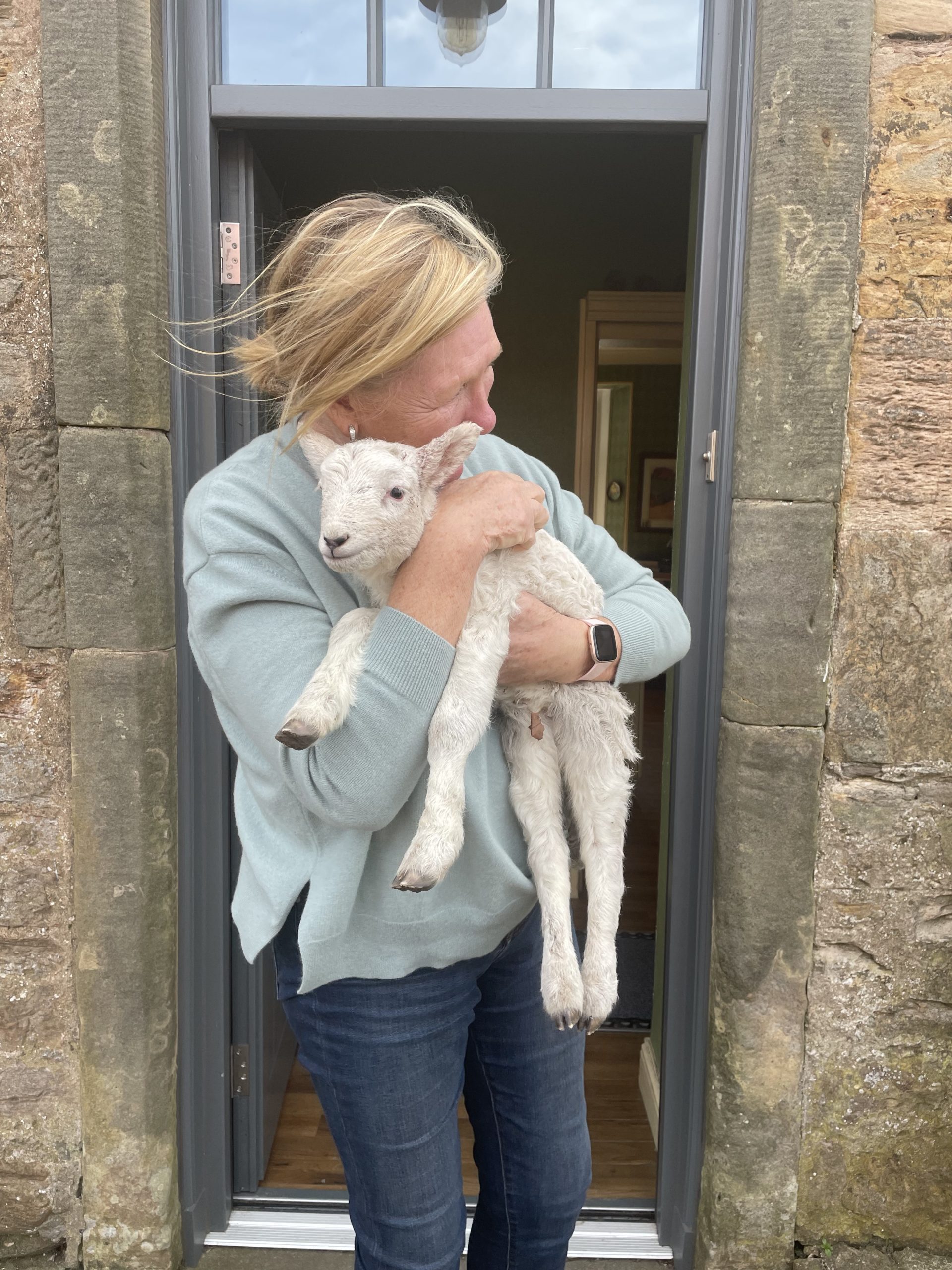 Woman cuddling a lamb