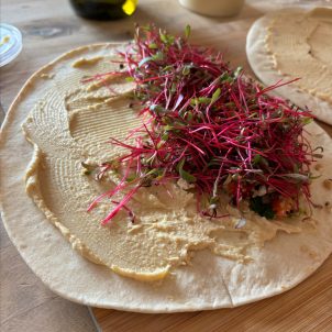 A wrap with houmous and pink microgreens on top.