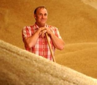 Rob standing in a pile of grain holding a shovel