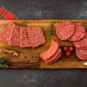 steak sausages, beef burgers and lorne sausages on a wooden chopping board with a tartan napkin