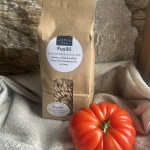 Fusilli Pasta in a brown bag with a beef tomato sitting in front