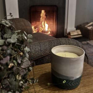 tallow candle sitting on table in front of a blazing fire