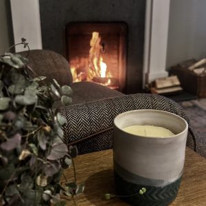 tallow candle sitting on table in front of a blazing fire