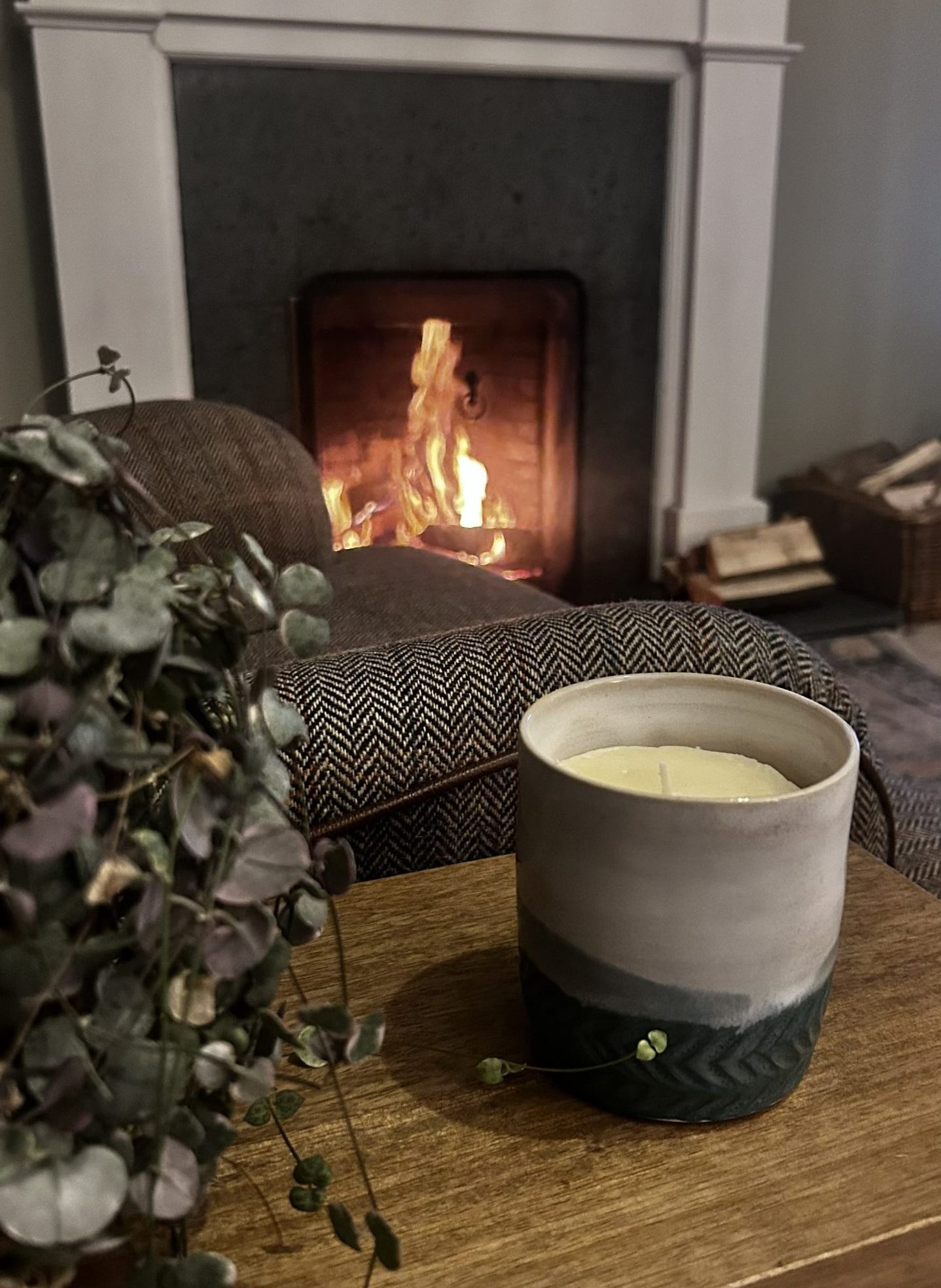 tallow candle sitting on table in front of a blazing fire
